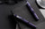 Purple pen and glasses on a black desk with a notebook