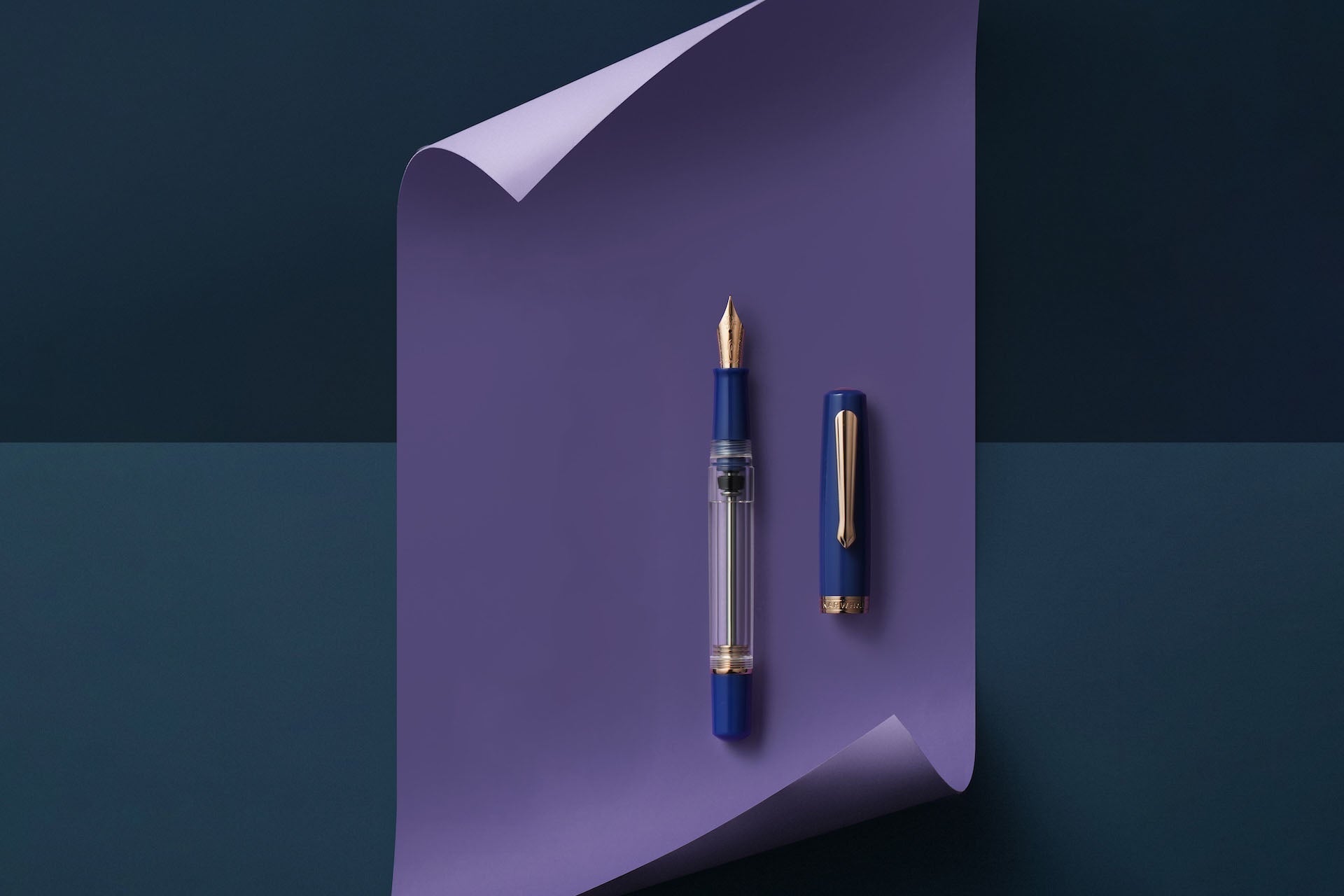 Fountain pen and its cap on a purple sheet of paper against a dark blue background