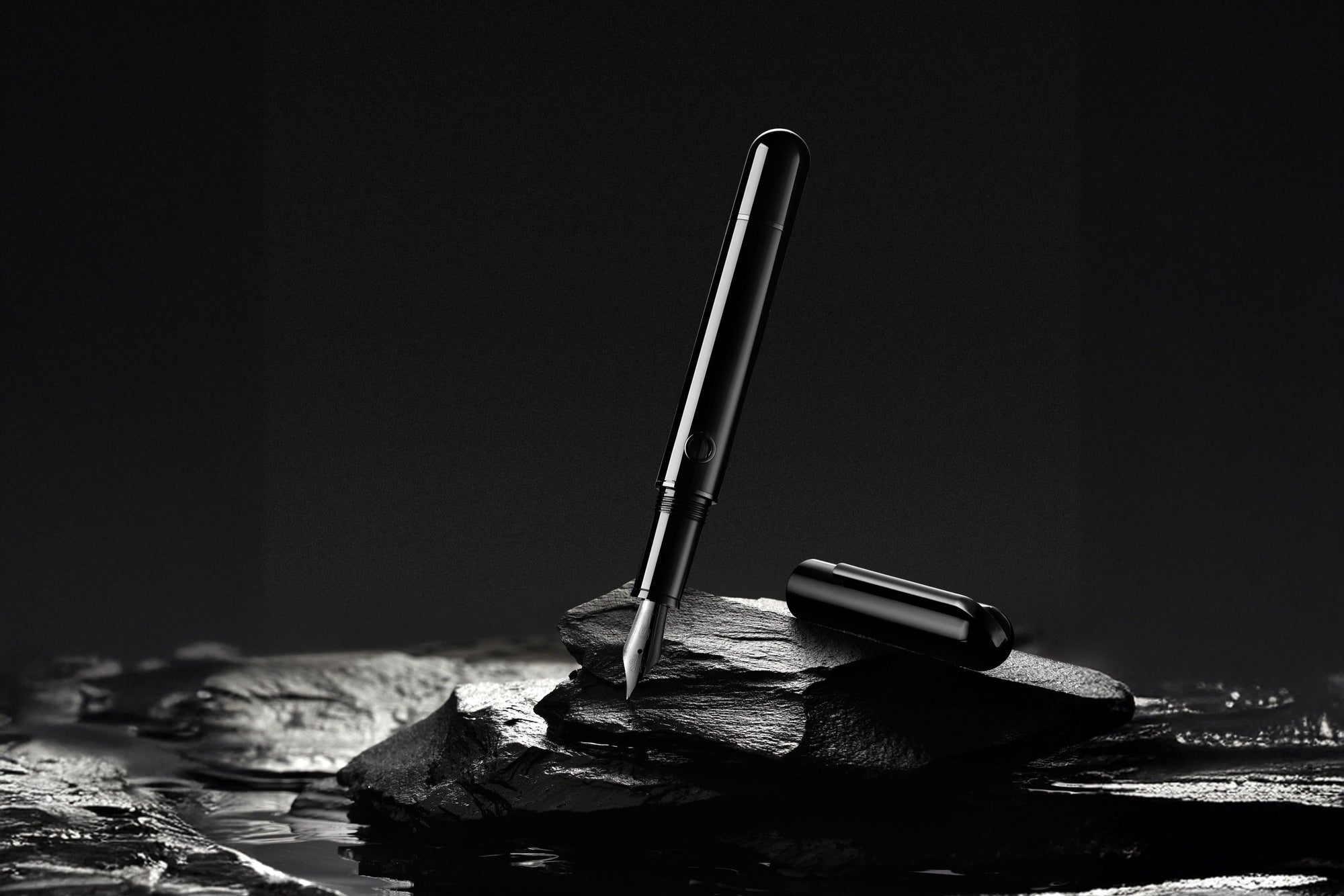 Black and white photo of a pen on a rock with a dark background