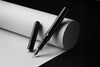 Fountain pen on a roll of paper with a black background